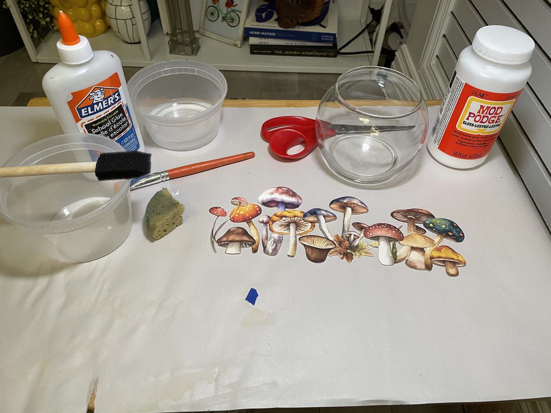 Cut-out mushroom illustrations laid out next to glue, Mod Podge, and a glass vase before being decoupaged.